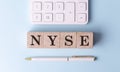 NYSE on wooden cubes with pen and calculator, financial concept