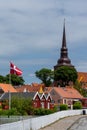 Red wooden houses and Danish flag with a tall church steeple behind Royalty Free Stock Photo