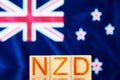 nzd concept. wooden blocks with the inscription nzd on background Flag of New Zealand.