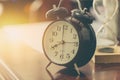 8 o`clock time retro clock with sand hourglass on wood table with sun light background Royalty Free Stock Photo