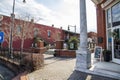 O`neal Plaza with red brick buildings, black metal fences, bare winter trees and lush green plants along Veterans Memorial Hwy