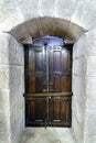 Oak door varnished with metal fittings and bar atranÃÂ¡ndola anchored in very thick granite stone walls in the palace of the Dukes