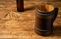 Oak mug with a handle and a glass brown bottle on a wooden table in a pub or bar. Handmade wooden tankard for beer or Royalty Free Stock Photo