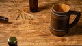 Oak mug with a handle and a glass brown bottle on a wooden table in a pub or bar. Handmade wooden tankard for beer or Royalty Free Stock Photo