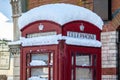 OAKHAM, RUTLAND, ENGLAND- 25 JANUARY 2021: Red telephone box covered in snow Royalty Free Stock Photo