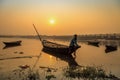 An oarsman sits on his boat to shore at sunset on river Damodar near the Durgapur Barrage.