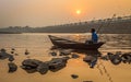 Oarsman sits on his boat to shore at sunset on river Damodar near the Durgapur Barrage.