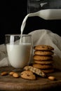 Oat cookies with pieces of chocolate, almond. Milk is poured into a glass with double walls from glass bottle Royalty Free Stock Photo