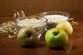 Oat ears stems and oat flakes and green apples in a bowl on a dark brown wood background. oat flakes big and small size grind.