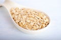 Oat flakes in big porcelain spoon on white background