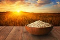 oat flakes in bowl on table with ripe cereal field on sunset as background Royalty Free Stock Photo