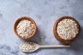 Oat flakes in bowl and wooden spoon isolated on wooden background, close-up, top view, selective focus. Royalty Free Stock Photo