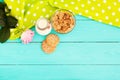 Oat flakes and cookies with jug of milk on blue wooden kitchen. Tablecloth in polka dots,pink rose. Selective focus. Mock up. Royalty Free Stock Photo