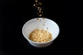 Oat flakes flying out of wooden bowl isolated on white and black background, falling oats Royalty Free Stock Photo