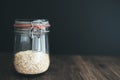 Oat flakes, oatmeal in weck glass jar on rustic wooden table against dark background