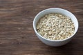 Oat flakes, rolled oatmeal in a white bowl on a wooden table Royalty Free Stock Photo