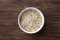 Oat flakes, rolled oatmeal in a white bowl on a wooden table Royalty Free Stock Photo