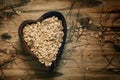 Oat flakes in a wooden bowl in the shape of a heart, top view