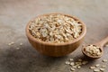 Oat flakes in a wooden bowl and wooden spoon on light brown background. Royalty Free Stock Photo