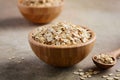 Oat flakes in a wooden bowl and wooden spoon on light brown background. Royalty Free Stock Photo