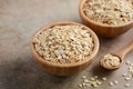 Oat flakes in a wooden bowl and wooden spoon on light brown background. Royalty Free Stock Photo