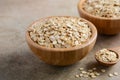 Oat flakes in a wooden bowl and wooden spoon on light brown background. Royalty Free Stock Photo