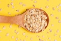 Oat flakes. Wooden spoon. Healthy eating. Yellow bright background
