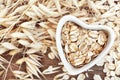 Oat groat in heart shaped bowl, oatmeal grain for healthy diet on oat ears plants background