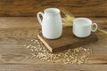 Oat milk in glass pitcher and oatmeal in a cup on a wooden table Royalty Free Stock Photo