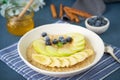 Oatmeal with bananas, blueberries, jam, honey, blue napkin on blue stone background. Close-up, side view