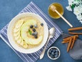 Oatmeal with bananas, blueberries, jam, honey, blue napkin on blue stone background. Close-up, top view