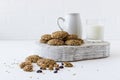 Oatmeal biscuits on a white wooden podium with a glass of milk, a jug opposite a white brick wall. delicious, healthy