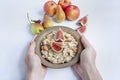 Oatmeal in a bowl with fresh figs, almonds and cashews. Oatmeal with fruits. Men`s hands hold a bowl of porridge. White backgroun