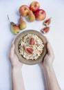 Oatmeal in a bowl with fresh figs, almonds and cashews. Oatmeal with fruits. Men`s hands hold a bowl of porridge. White backgroun