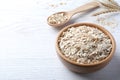 Oatmeal, bowl and spoon on white wooden table. Space for text