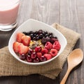 Oatmeal in bowl topped with fresh blueberries, cranberries, strawberries, raspberries, blackberries and berry smoothie. Royalty Free Stock Photo