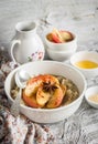 Oatmeal with caramelized apples and cinnamon in a white bowl on a light wooden background