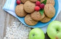 Oatmeal cookies with berry raspberries in a Cup of the green apples next to a bunch of flakes oatmeal