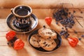 Oatmeal cookies and coffee in sunlight on a wooden background with physalis and wild forest berries