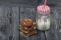 Oatmeal cookies with peanuts and chocolate. Folded in a column and laid out with paper. Nearby milk. On pine boards Royalty Free Stock Photo