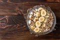 Oatmeal with cottage cheese, sunflower seeds and banana on dark wooden background with yellow tulips