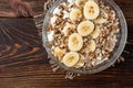 Oatmeal with cottage cheese, sunflower seeds and banana on dark wooden background with yellow tulips