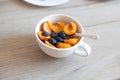 Oatmeal with different berries in bowl on wooden table