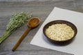 Oatmeal flakes in a ceramic bowl with a wooden spoon and ears of oats on a linen napkin on a wooden table background Royalty Free Stock Photo