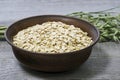 Oatmeal flakes in a deep ceramic brown dark bowl close-up against green oat ears on an old faded gray wooden table Royalty Free Stock Photo