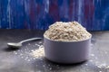 Oatmeal flakes in a deep lilac ceramic deep bowl, in the distance a vintage spoon.