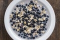 Oatmeal with fresh blueberry, almond milk and honey for breakfast in plate on wooden background. Rustic style. Top view Royalty Free Stock Photo