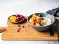 Oatmeal with fresh tangerine slices and pomegranate seeds, ground almonds and mint in a blue bowl on wood board. Copy space