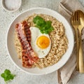 Oatmeal, fried egg, fried bacon. Hearty fat high-calorie breakfast, top view