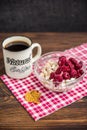 Oatmeal with frozen cherry with cup of coffee on wooden background Royalty Free Stock Photo